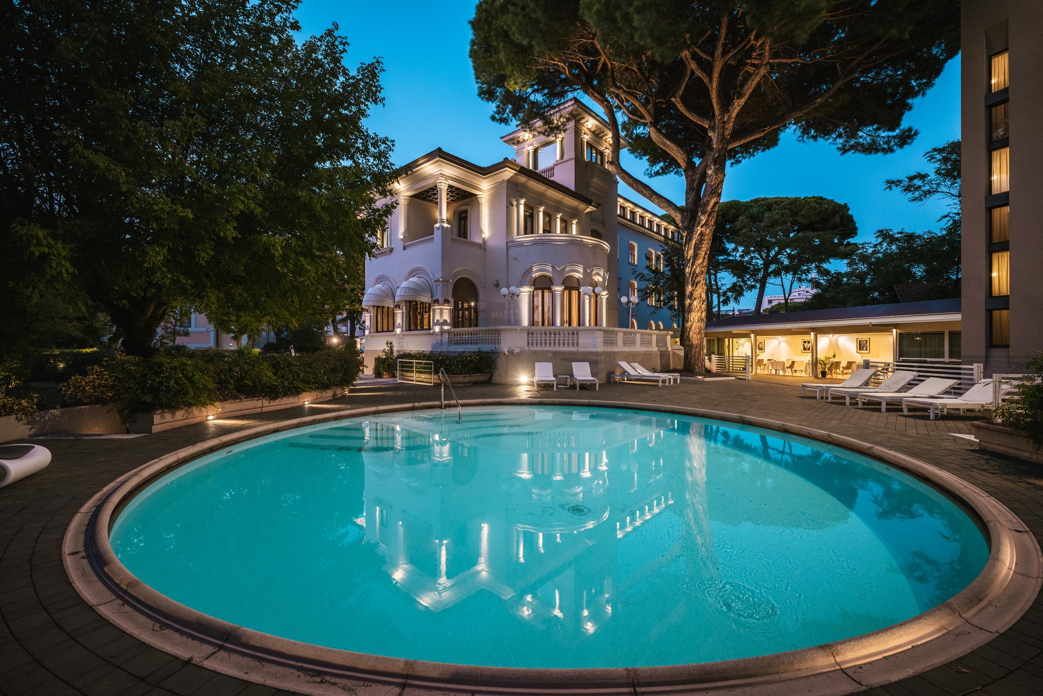 De La Ville – Rond zwembad bij avond, Riccione